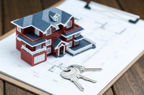 Villa house model, key and drawing on retro desktop (real estate sale concept)